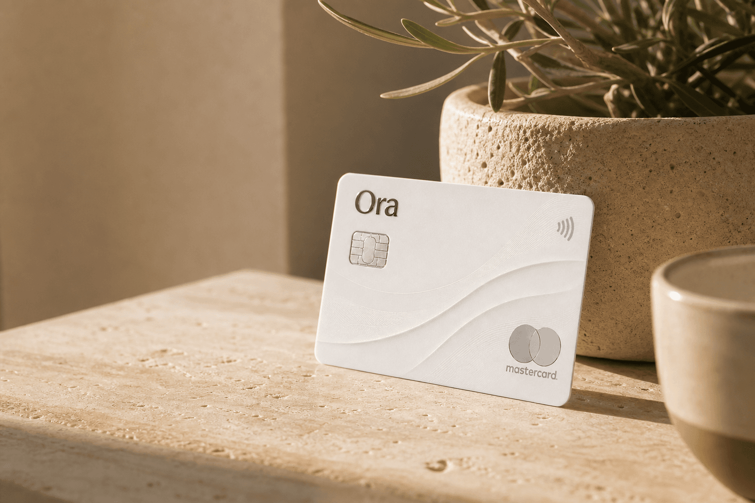 An Ora business card resting on a warm, sunlit desk
